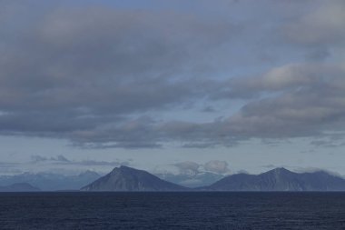 Alaska Körfezi 'ndeki bir yolcu gemisinden görülen adalar ve karla kaplı dağlar sisli bir sabah denizinde.