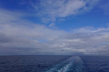 Derin mavi gökyüzünde bulutlar ve Alaska Körfezi 'nde bir yolcu gemisinin ardından.