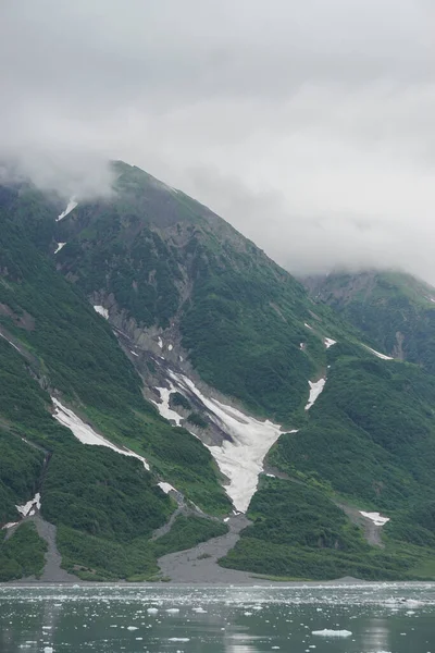 米国アラスカ州ヤカット湾 ヤカット湾の明るい緑の水の端にある山の中腹に降りる雲 — ストック写真