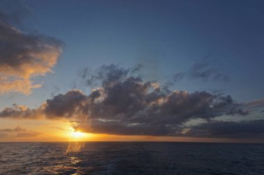 Güneş, Sitka, Alaska ve Victoria, British Columbia, Kanada arasındaki Kuzey Pasifik Okyanusu 'ndan batarken ufukta yoğun beyaz bulutlar beliriyor..