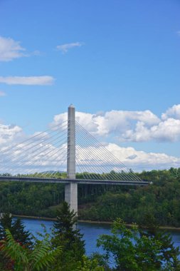 Bucksport, Maine, ABD: Penobscot Narrows Köprüsü üzerinde açık mavi gökyüzünde beyaz bulutlar. Köprü, Penobscot Nehri üzerinde halatla kurulmuş uzun bir köprüdür..