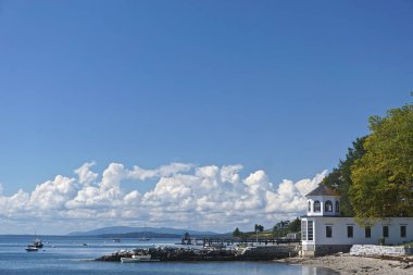 Castine, Maine, ABD: Castine limanı üzerinde mavi gökyüzünde güzel beyaz bulutlar, Penobscot Körfezi 'nde küçük kayıklar ve uzaktaki dağlar.