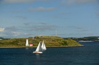 Halifax, Nova Scotia, Kanada: Arka planda Georges Adası deniz feneri ve Fort Charlotte ile Halifax Limanı 'nda yarış yapan yelkenliler.