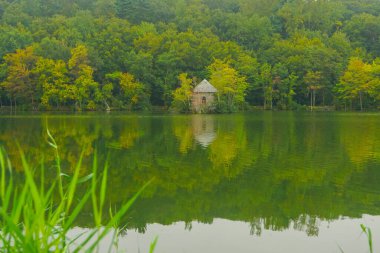 Tarrytown, New York, ABD: Tarrytown Reservoir 'da küçük bir taş bina, arka planda sonbahar yeşillikleri var.