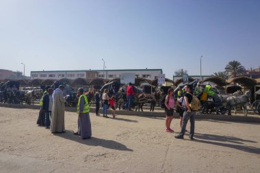 Ziyaretçiler, Nil yolcu gemilerine dönüş yolculukları için Horus Tapınağı yakınlarındaki bir meydanda at taksisi bekliyorlar..