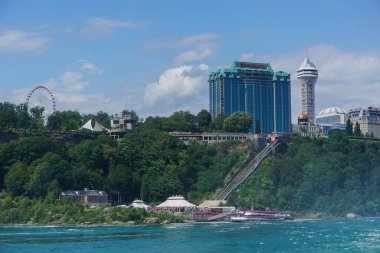Niagara Şelalesi, New York: Yolcular Niagara Şelalesi 'ni yakından görebilmek için tur teknelerini dolduruyor, arka planda aynı isimli Kanada şehri bulunuyor..