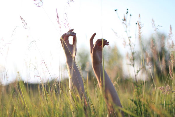the girl raises her hands to the sky, being in the grass on the meadow