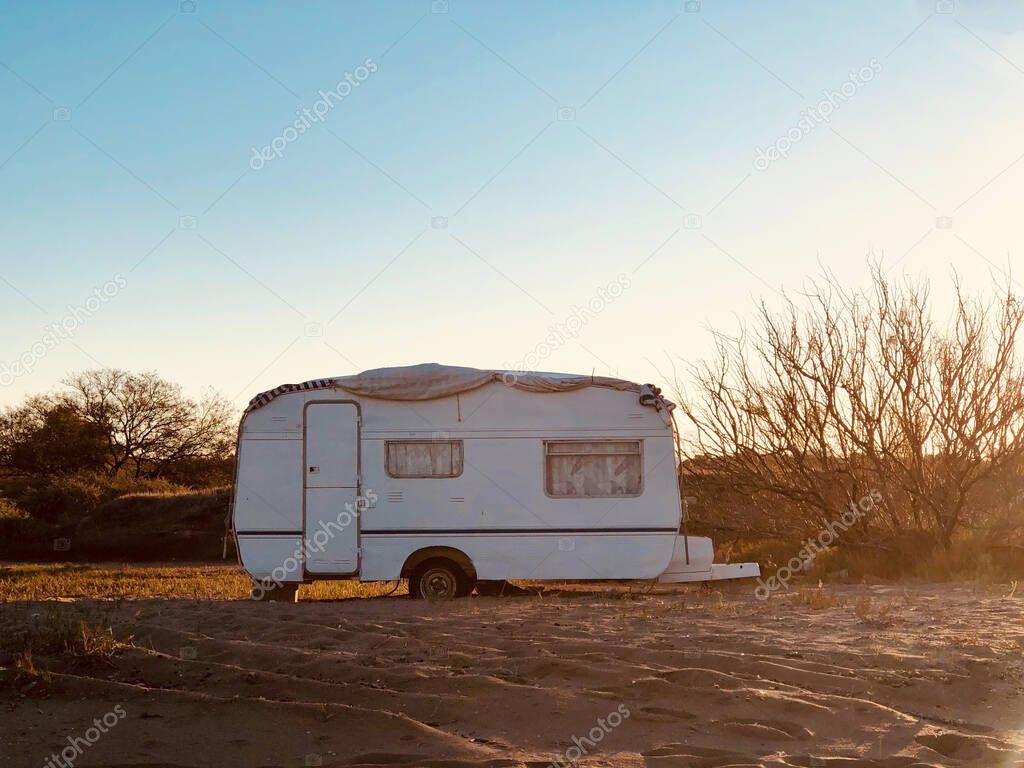 White, medium size vintage caravan without logos in a parking spot landscape  at sunrise time. Adventure, outdoor recreation, adventures in nature, vacation. 