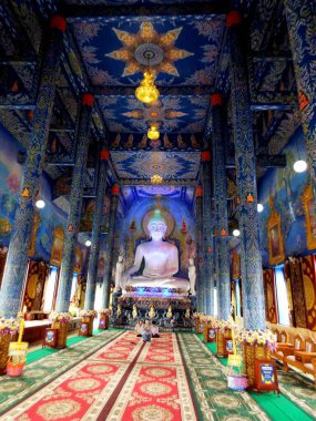 Chiang Rai. Tayland, 16 Haziran 2017 Wat Rong Suea 10. Chiang Rai 'deki Mavi Tapınak' ta üç kişinin fotoğrafı çekiliyor. Duvarlarında Buda resmi ve renkli süslemeler var. Tayland (dikey görünüm)