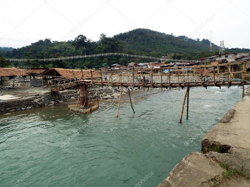 Wooden bridge over the Bahorok river as it passes through Bukit Lawang with the mountain in the background in the North Sumatra province of Indonesia.