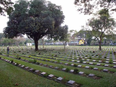 Kanchanaburi, Tayland, 26 Ocak 2013: Bir adam 2. Dünya Savaşı Savaşçıları Askeri Mezarlığı 'nda bir mezara bakıyor..