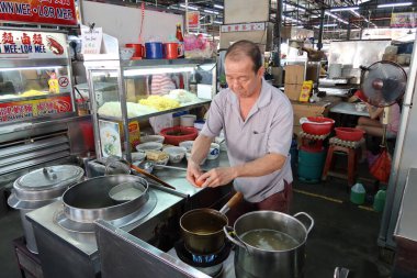 Georgetown, Penang, Malezya, 4 Ocak 2020: Georgetown, Malezya 'daki Pasar Lebuh Cecil pazarında yemek pişiren bir adam.