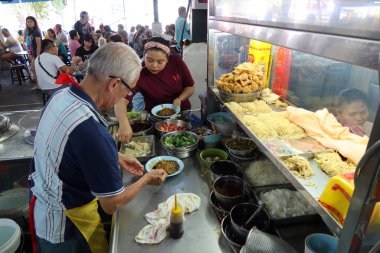 Georgetown, Penang, Malezya, 4 Ocak 2020: Bir erkek ve bir kadın Georgetown, Malezya 'daki Pasar Lebuh Cecil Marketinde bir tabak erişte hazırlıyorlar..