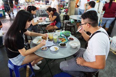 Georgetown, Penang, Malezya, 4 Ocak 2020: İnsanlar Georgetown, Malezya 'daki Pasar Lebuh Cecil Market' in masalarında yemek yiyorlar.