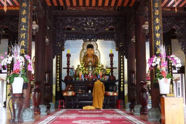 Hoi An, Vietnam, 3 Mart 2020 bir tapınağın sunağında Buda heykelinin önündeki Budist keşiş. Hoi An, Vietnam