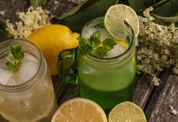 Ev yapımı Elderflower limonata, limon dilimi ve ahşap arka planda nane..