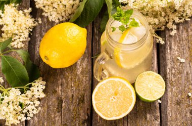 Ev yapımı Elderflower limonata, limon dilimi ve ahşap arka planda nane..