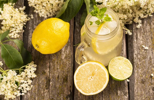 Ev yapımı Elderflower limonata, limon dilimi ve ahşap arka planda nane..