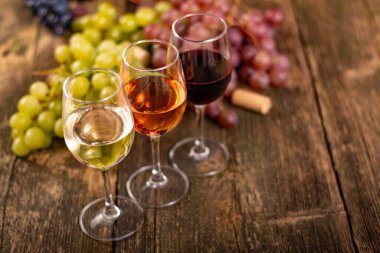 Ahşap masada üzümlü bir şişe kırmızı şarap..