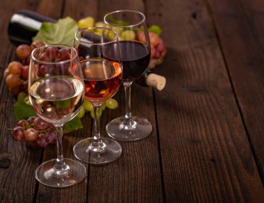 Ahşap masada üzümlü bir şişe kırmızı şarap..