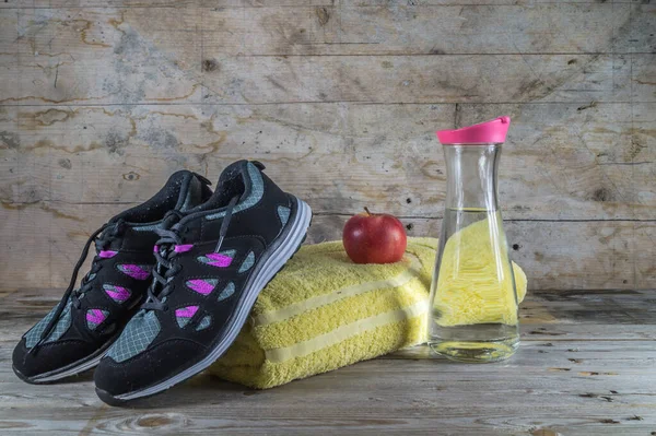 Spor antrenmanı konsepti. Bir çift spor ayakkabı, yemek için bir elma ve içmek için biraz su..