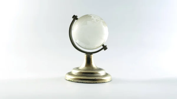 Beyaz kristal şeffaf Globe ya da globus izole top metal altın çerçeve üzerinde duran temiz beyaz arka plan. Dünya haritasını küçük kristal kürede gösteren şeffaf bir dünya, insanların eğitilmesine ve dünya hakkında bilgi verilmesine yardımcı olur..