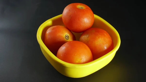 Yeşil kasede su damlacıkları olan kırmızı domatesler.