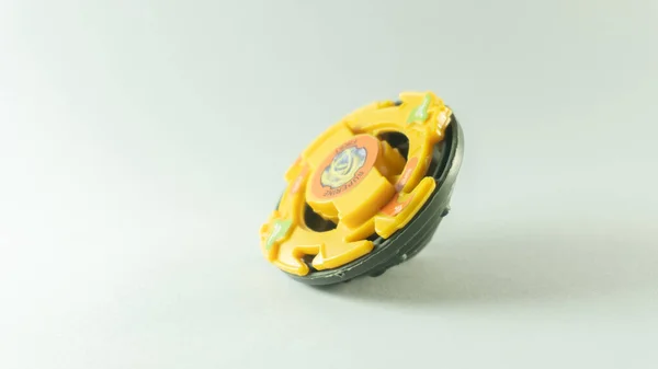 Sarı renkli plastik oyuncak, beyaz arkaplanda kendi pozisyonunda hızla döner.