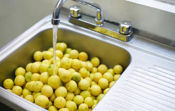 washing lemons, water falling from tap, disinfecting lemons, disinfecting fruit, selective focus, water tap