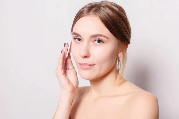 Woman using cotton pad. Happy smiling beautiful young woman cleaning skin by cotton pad. light background. Beautiful Spa Woman Smiling. Perfect Fresh Skin. Youth and Skin Care Concept