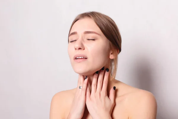 Hastalık, sağlık, insan, tıp kavramı - boğaz ağrısı. Closeup boğaz duygu kötü, ağrılı yutma acı ile hasta bir kadın. Güzel kız boyun el ile dokunmak
