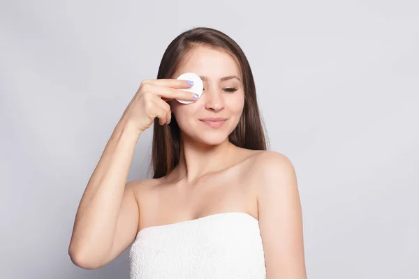 Woman using cotton pad. Happy smiling beautiful young woman cleaning skin by cotton pad. light background. Beautiful Spa Woman Smiling. Perfect Fresh Skin. Youth and Skin Care Concept