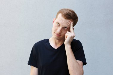 Moda, stil, duygular ve insanlar kavramı - Kızıl çilli bir gri ile güzel bir erkekçe adamın portresi yakından arka plan siyah T-shirt. bir el tarafından tapınağın ikindilerde tutar