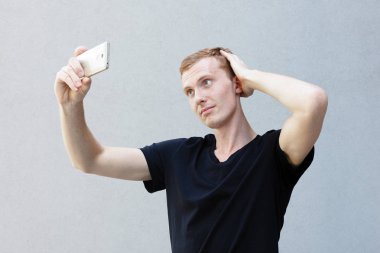 Moda, stil, duygular ve insanlar kavramı - Kızıl çilli ile güzel bir erkekçe adamın portresi yakından. Selfie zaman, blogger onu sosyal ağlar sayfası için fotoğraf yapıyor.