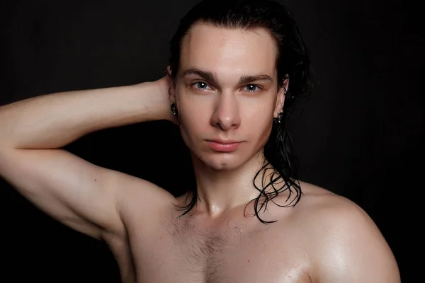 people, skincare and beauty concept - Wet young man with long black hair on a black background. Portrait male with shaved chest . Men\'s skin care. Ripped muscular handsome man on black background