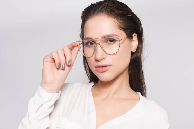 Beyaz boş t-shirt giyen gözlük, boş duvar, stüdyo portre, Genç ve güzel kız. Gözlük gülümseyen esmer kadın