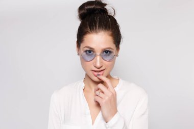 Beyaz boş t-shirt giyen gözlük, boş duvar, stüdyo portre, Genç ve güzel kız. Gözlük gülümseyen esmer kadın