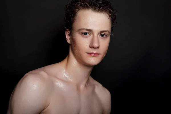 people, skincare and beauty concept - Wet young man with black hair on a black background. Portrait male with shaved chest . Men\'s skin care. Ripped muscular handsome man on black background