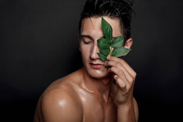 people, skincare and beauty concept - Wet young man with black hair on a black background. Portrait male with shaved chest . Men's skin care. Ripped muscular handsome man on black background