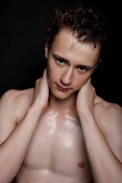 people, skincare and beauty concept - Wet young man with black hair on a black background. Portrait male with shaved chest . Men\'s skin care. Ripped muscular handsome man on black background