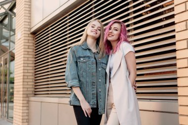 Şehirde takılmak süre kucaklayan hipster Genç Yetişkin arkadaşlar. İki genç kadın gülüyor ve kaygısız tatil yaşam tarzı zevk yürüyüş