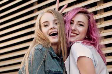Şehirde takılmak süre kucaklayan hipster Genç Yetişkin arkadaşlar. İki genç kadın gülüyor ve kaygısız tatil yaşam tarzı zevk yürüyüş