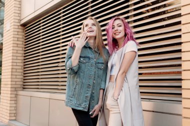 Şehirde takılmak süre kucaklayan hipster Genç Yetişkin arkadaşlar. İki genç kadın gülüyor ve kaygısız tatil yaşam tarzı zevk yürüyüş