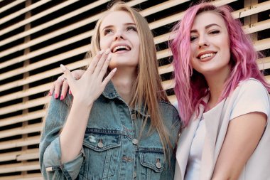 Şehirde takılmak süre kucaklayan hipster Genç Yetişkin arkadaşlar. İki genç kadın gülüyor ve kaygısız tatil yaşam tarzı zevk yürüyüş