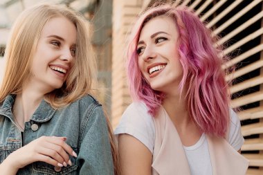 Şehirde takılmak süre kucaklayan hipster Genç Yetişkin arkadaşlar. İki genç kadın gülüyor ve kaygısız tatil yaşam tarzı zevk yürüyüş