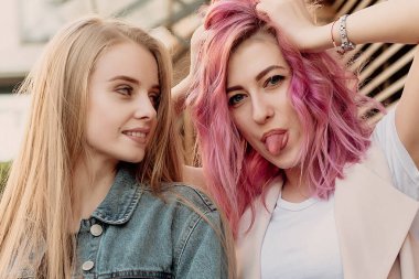 Şehirde takılmak süre kucaklayan hipster Genç Yetişkin arkadaşlar. İki genç kadın gülüyor ve kaygısız tatil yaşam tarzı zevk yürüyüş