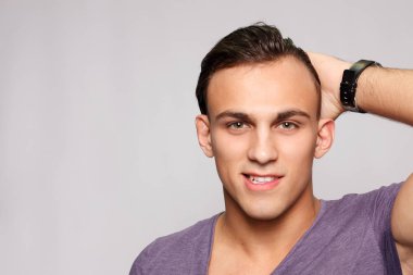 duygu, reklam ve insanlar kavramı - yakışıklı genç adam kameraya bakarak gri arka plan üzerinde. Seksi bir adam portresi. Mutlu erkek gülümseyen.