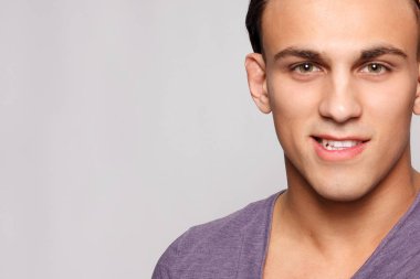duygu, reklam ve insanlar kavramı - yakışıklı genç adam kameraya bakarak gri arka plan üzerinde. Seksi bir adam portresi. Mutlu erkek gülümseyen.