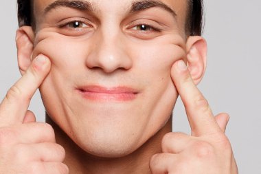 duygu, reklam ve insanlar kavramı - yakışıklı genç adam kameraya bakarak gri arka plan üzerinde. Seksi bir adam portresi. Mutlu erkek gülümseyen.