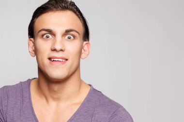 duygu, reklam ve insanlar kavramı - yakışıklı genç adam kameraya bakarak gri arka plan üzerinde. Seksi bir adam portresi. Mutlu erkek gülümseyen.